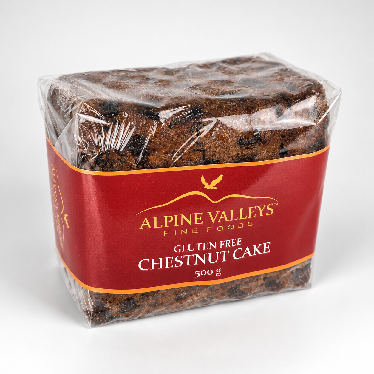 Angled view of Alpine Valleys Fine Foods Gluten Free Chestnut Cake 500g, showing the rich dark cake texture, clear wrapping and red branded packaging.